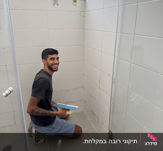 אדם עובד על תיקון אריחים בחדר אמבטיה